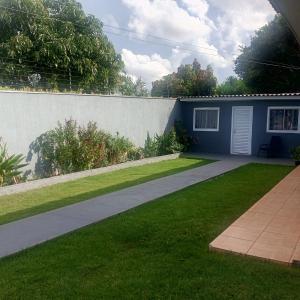 a garden with a concrete wall and a lawn at Suíte completa na Região do Lago in Cascavel