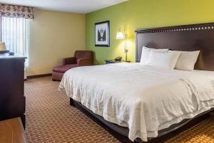 a hotel room with a large bed and a chair at Wingate by Wyndham Conway AR in Conway