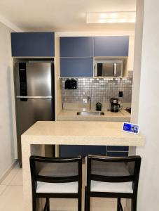 a kitchen with a counter with two chairs and a refrigerator at apartamento Seminate 2 in Franca