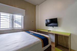 a bedroom with a bed and a tv on the wall at Hotel Dahlia By ARBA in Jakarta