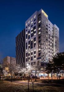 a tall building at night with trees in front of it at Gold Coast Hotel Incheon in Incheon