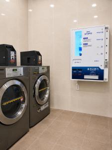a laundry room with two washing machines and a screen at Gold Coast Hotel Incheon in Incheon