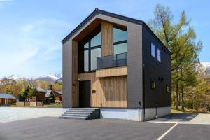 a black and wooden house with a lot of windows at Forest Resort Oak in Hakuba