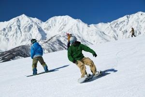 three people are snowboarding down a snow covered mountain at Forest Resort Oak in Hakuba
