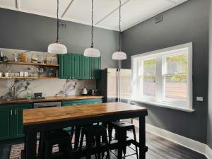 a kitchen with green cabinets and a wooden table at Forrest House Victor Harbor in Victor Harbor