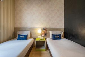 two beds in a small room with a table at Hotel Dahlia By ARBA in Jakarta