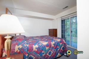 a bedroom with a bed and a lamp and a window at Senedo Springs Duplex #97A in Basye