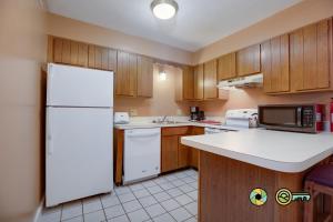 a kitchen with a white refrigerator and wooden cabinets at Senedo Springs Duplex #97B in Basye +29 photos