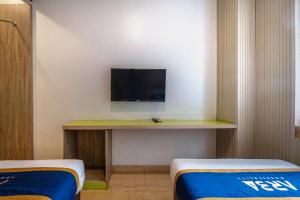 a room with a desk with a tv on a wall at Hotel Dahlia By ARBA in Jakarta +15 photos