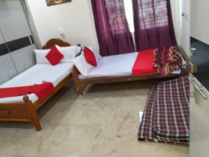 two beds in a room with red and white pillows at Mahadev grand in Tirupati
