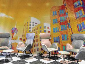 a group of chairs and tables in front of a mural at ibis Duesseldorf Airport in Düsseldorf
