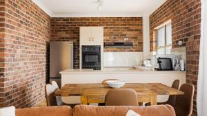 a kitchen and dining room with a brick wall at North Street Panorama in Urunga