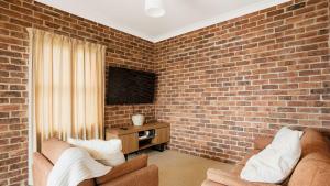 a living room with a brick wall at North Street Panorama in Urunga +7 photos