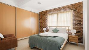 a bedroom with a bed and a brick wall at North Street Panorama in Urunga