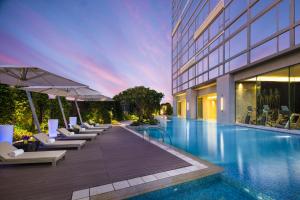 a swimming pool with lounge chairs and a building at Ascott Macau in Macau