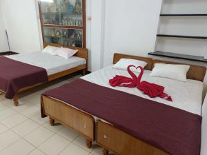 two beds with red bows on them in a room at Adb's Kuzhlam Traditional Homestay & Rooms in Tiruchirappalli