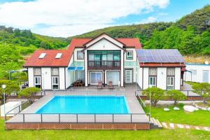 a house with a swimming pool in the yard at Anmyeondo Chingunae Pension in Taean