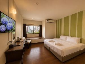 a bedroom with a bed and a desk and a television at Woraburi Sukhumvit Hotel in Bangkok +44 photos