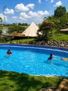 two people in a swimming pool with a tent in the background at Zenna Lake Retreat in Tien Xuan