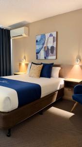 a hotel room with a large bed and a blue chair at The Metropolitan Spring Hill in Brisbane +32 photos