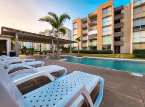 a row of white lounge chairs next to a swimming pool at Relax Terrace Condo Near Coronado Beaches in El Creo