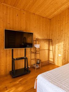 a bedroom with a flat screen tv in a wooden wall at Zenna Lake Retreat in Tien Xuan