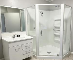 a white bathroom with a shower and a sink at Cube Lite Apartments in Hamilton