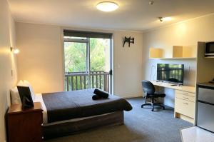 a bedroom with a bed and a desk and a television at Cube Lite Apartments in Hamilton +8 photos