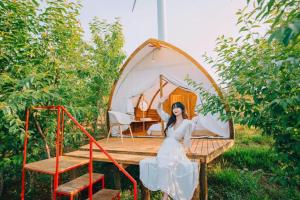 a woman in a white dress standing in front of a tent at Trạm Mây Glamping in Da Lat