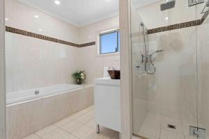 a bathroom with a shower and a tub and a sink at Sunkissed & Studio in Vincentia +18 photos