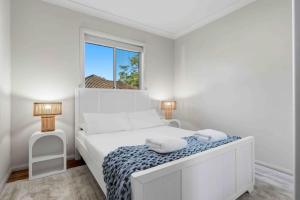 a white bedroom with a bed and a window at Sunkissed & Studio in Vincentia