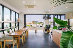 a dining room with tables and chairs and large windows at Dorami Pension in Seogwipo