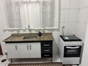 a small kitchen with a sink and a stove at Casa 2 dorms com garagem e Wi-Fi in São Paulo