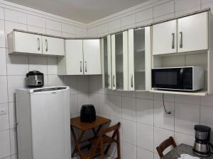 a kitchen with white cabinets and a microwave at Casa 2 dorms com garagem e Wi-Fi in São Paulo