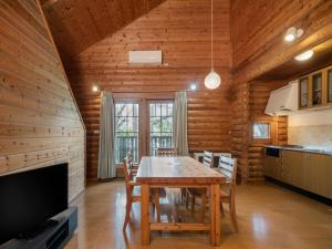 a dining room with a wooden table and a television at AZUMINO KOGEN Resort in Azumino