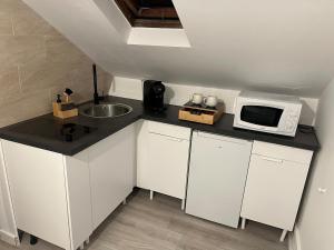 a small kitchen with a microwave and a sink at Cocon 2 pièces - Design premium in Alfortville