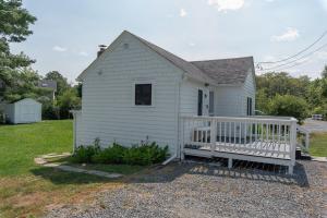 a white house with a bench in front of it at Shorebreak Cottage in North Kingstown