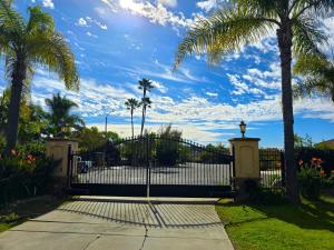 a gate with palm trees and a blue sky at Morning Glory Retreat-Private Lux 1-Bedroom Suite in a Tropical Resort Setting in Vista
