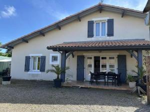 a white house with a black table on a deck at Le gîte sabotier in Nerbis