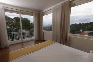 a bedroom with a bed and two large windows at Green Royal Villa in Kandy