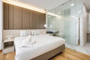 a bedroom with a large white bed and a glass shower at Societe Hartamas in Kuala Lumpur