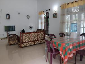 a dining room with a table and chairs and a tv at Muthu Villa in Negombo