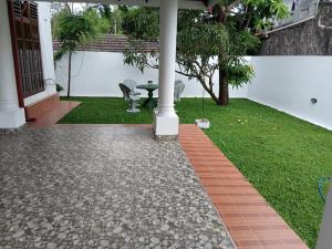 a patio with a table and a grass yard at Muthu Villa in Negombo