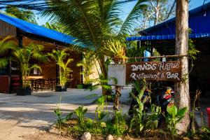 a sign in front of a restaurant with palm trees at David's Hostel & Restaurant in Kaôh Rŭng (3)
