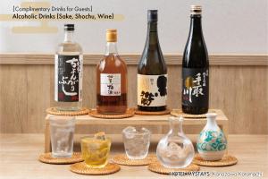 a group of wine bottles and glasses on a shelf at HOTEL MYSTAYS Kanazawa Katamachi in Kanazawa