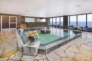 a swimming pool with flowers in a building at Hotel Resorpia Atami in Atami