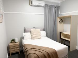 a small bedroom with a bed and a window at Port Macquarie Hotel in Port Macquarie