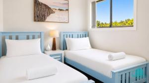 two beds in a room with two windows at Beachside Beauty in Caves Beach