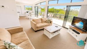 a living room with a couch and a tv at Beachside Beauty in Caves Beach