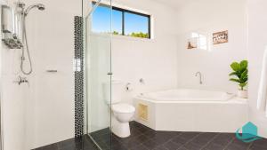 a bathroom with a tub and a toilet and a sink at Beachside Beauty in Caves Beach +10 photos